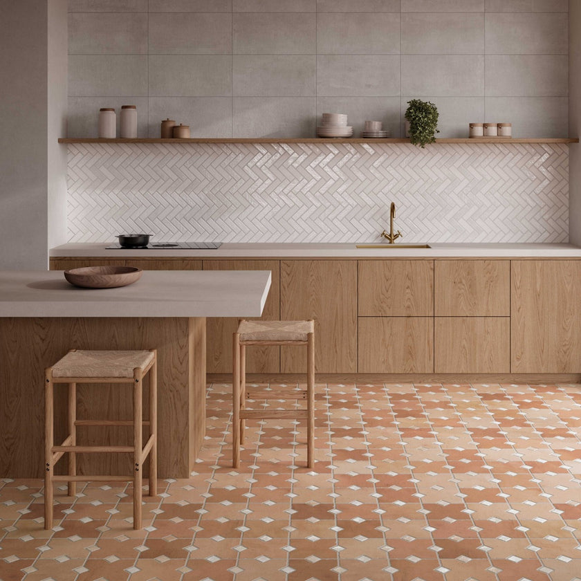 Carrelage Kurios Cotto posé au sol, aux nuances beige et terre cuite avec cabochons clairs, près de marches et d’un mur végétalisé. 